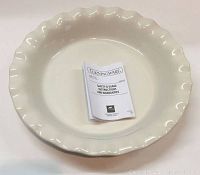 Two large fluted edge beige CorningWare pie dish plates with safety and usage instructions booklet on one plate.