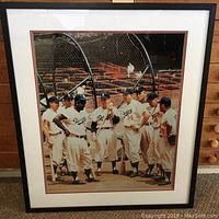 Front view of large framed color photograph showing Brooklyn Dodgers players grouped on a baseball field with batting cage in background.