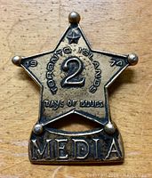 Front view of vintage 1974 metal star-shaped media badge with "2" number and "Toronto Islands Days of Blues" embossed text, showing patina and wear.