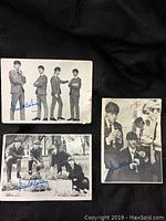 Three vintage Beatles cards showing the group in black and white photos with facsimile Paul McCartney signatures, laid on a dark fabric background.