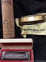 Hohner and Clarke harmonicas with their cases and cloth pouches.