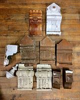 Top-down view of all 12 solid wood architectural pieces arranged on wooden floor, showing variety in shape, size, and finish.