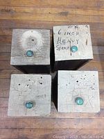 Top view of four vintage wooden drawers arranged in a square, showing heavily crackled off-white paint surfaces and green knobs. One drawer has '6 INCH HEAVY STRAP' handwritten on top.