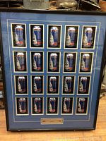 Full framed collection showing 24 NHL Stanley Cup championship beer cans from Labatt Blue arranged in a 6 by 4 grid with blue matting and black frame.
