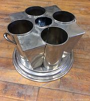 Silver-plated bottle holder showing top view with five cylindrical compartments on a round base.