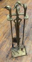 Full view of the brass fireplace tool set showing all five tools with goose head handles standing in the base