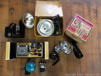 Overview of two Brownie cameras and vintage camera accessories on wooden floor.