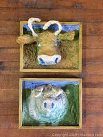 View of the pair of folk art 3D cow head wall hangings showing the front and some texture.