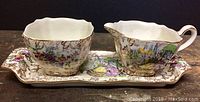 Full view of the creamer, sugar bowl, and tray showing colorful and detailed designs typical of Lord Nelson Ware with gold accents.
