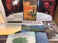 Photo showing all seven books together on a surface, two hardcovers and five softcovers about Canada with various cover images including portrait and landscape photography.