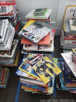 Photo showing many stacked children's books, colorful covers visible including a Transformers themed book and other varied titles
