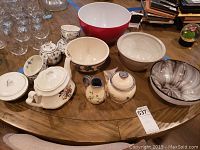 Photo of the tea set items on a wooden table including teapots, bowls, creamer, sugar bowl, and small covered bowl