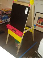 Wooden easel front view with black chalkboard and red chalk holder