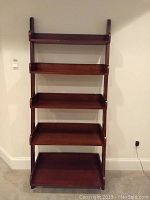 Front view showing five open shelves with raised edges and dark wood finish.