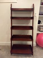 Front view of the tall wooden bookcase with five shelves and visible wear marks