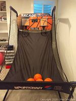 Full frontal view of the Sportscraft Arcade Hoops game showing two basketball hoops, canvas play ramp, four mini basketballs on the ramp and the Sportscraft logo on the bottom canvas.