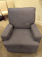 Front view of the blue upholstered recliner chair showing cushion and armrests.