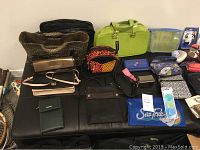 Full view of wallets, purses, small toiletry bags, handbags, laptop bags, duffel bag, and backpack assorted on a couch and floor showing colors, sizes, styles, and materials