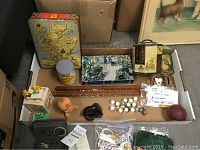 Lot overview showing vintage tins, glass marbles in a box, thimbles, small figurines, a hair brush, and a wooden tie and belt hanger.