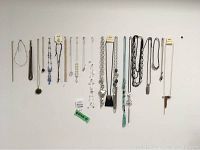 Full view of 17 costume jewellery necklaces of varied styles and lengths displayed hanging on a wall.