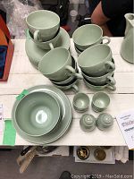 Top view showing multiple stacked tea cups, saucers, egg cups, salt and pepper shakers, and side plates with a bowl in the middle.