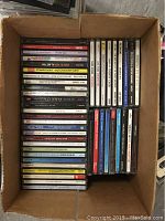 Photo of a box containing about 30 classical music CDs neatly stacked, titles including Tchaikovsky Nutcracker Suite and various piano concertos.