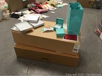 Two large cardboard cases stacked with silver textured jewelry boxes and Tiffany blue boxes on top.