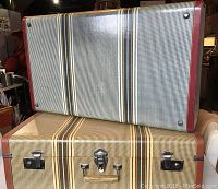 Two suitcases stacked showing patterned vinyl exterior and trim