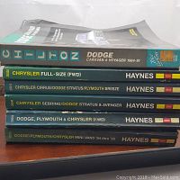 Stack of six automotive repair manuals for Dodge and Chrysler vehicles, showing titles and visible wear marks.