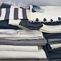 Stack of various folded fabric remnants in black, white, gray, and striped pattern