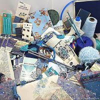 Entire assortment of blue and pastel colored arts and crafts items including fabric, yarn, needlework tools, and sewing accessories.