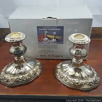 Pair of silverplate console candlesticks on display with the original box behind them, showing overall design, size, and condition.