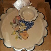Scalloped edge pottery platter with fruit artwork inside, cream base color with painted grapes and pears.