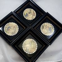 Four black shadowbox frames arranged showing vintage hand tinted prints with scalloped round central windows.