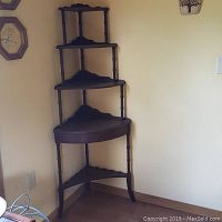 Full view of the antique dark wooden corner shelf showing its five triangular shelves and three-legged base.