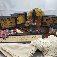 Full view of all items included in the steampunk box lot arranged on white surface, showing framed signs, bells, decorative car cutout, and fabric pieces.