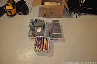 Overview of collection including music CDs in jewel cases, DVDs, and VHS tapes in boxes on the floor
