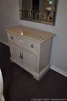 Front angle view of the light cream wood server cabinet with decorative drawer front and double cupboard doors, no contents inside.