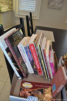 Books arranged upright in a box showing various titles related to Asian cooking, cookies, and other cuisines.