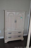 Front view of light wood armoire with closed double doors and two drawers
