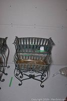 Front view of large and smaller metal planters with basket design and scrollwork legs