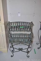 Front view of two metal planters side by side, showing lattice sides and scroll legs