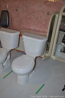 Front and angled view of the white Crane Plumbing toilet showing the full unit and seat height.