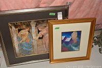 Two framed pictures side by side: large angel-themed artwork and smaller colorful farmhouse pastel painting.