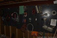 Wide shot of pegboard with plumbing and electrical parts hanging including coiled wiring, connectors, and bags of small parts