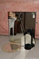 All three mirrors shown: two oval mirrors with ivory decorative frames and one rectangular mirror with black edges, along with white laundry sink and pedestal base in basement setting.