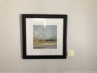 Square abstract art painting with black frame hanging on wall, showing grey, yellow, and brown tones.