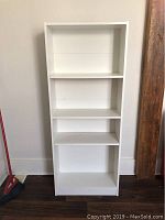 Front view of white wooden shelving unit showing five shelves and overall height and width.