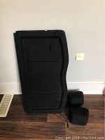 Privacy cover panel and two black headrests positioned against a wall on wooden laminate floor.