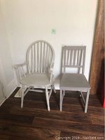 Photo of two gray painted wooden chairs, one armchair with spindle back and one straight-backed dining chair.